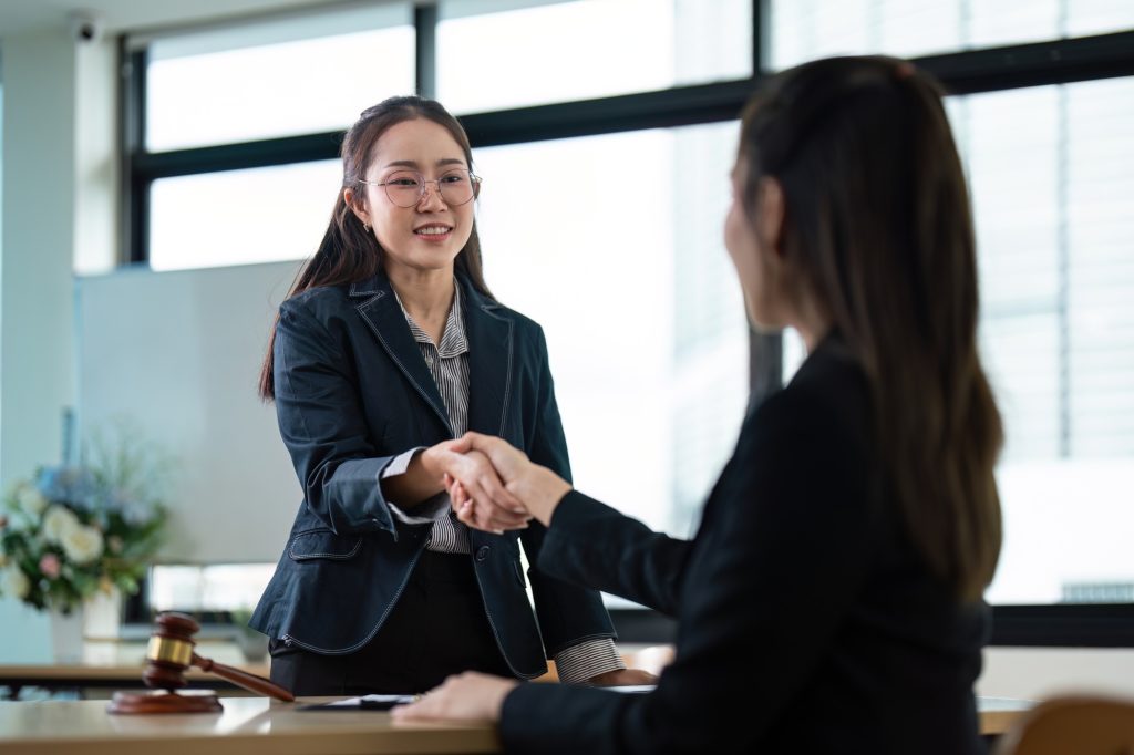 Professional Female Lawyer Shaking Hands with Client in Modern Office Setting, Legal Consultation