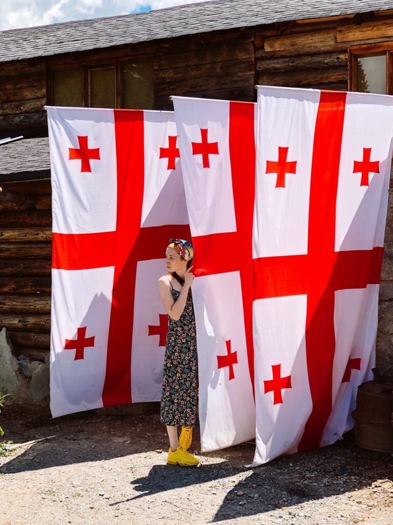 summer. a girl near three huge Georgian flags